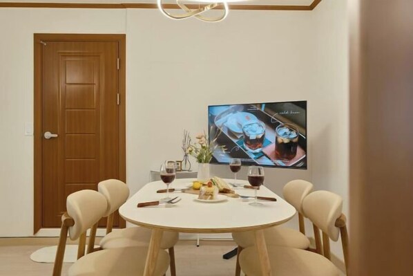A dining area with a round table, chairs, a television, and a door.
