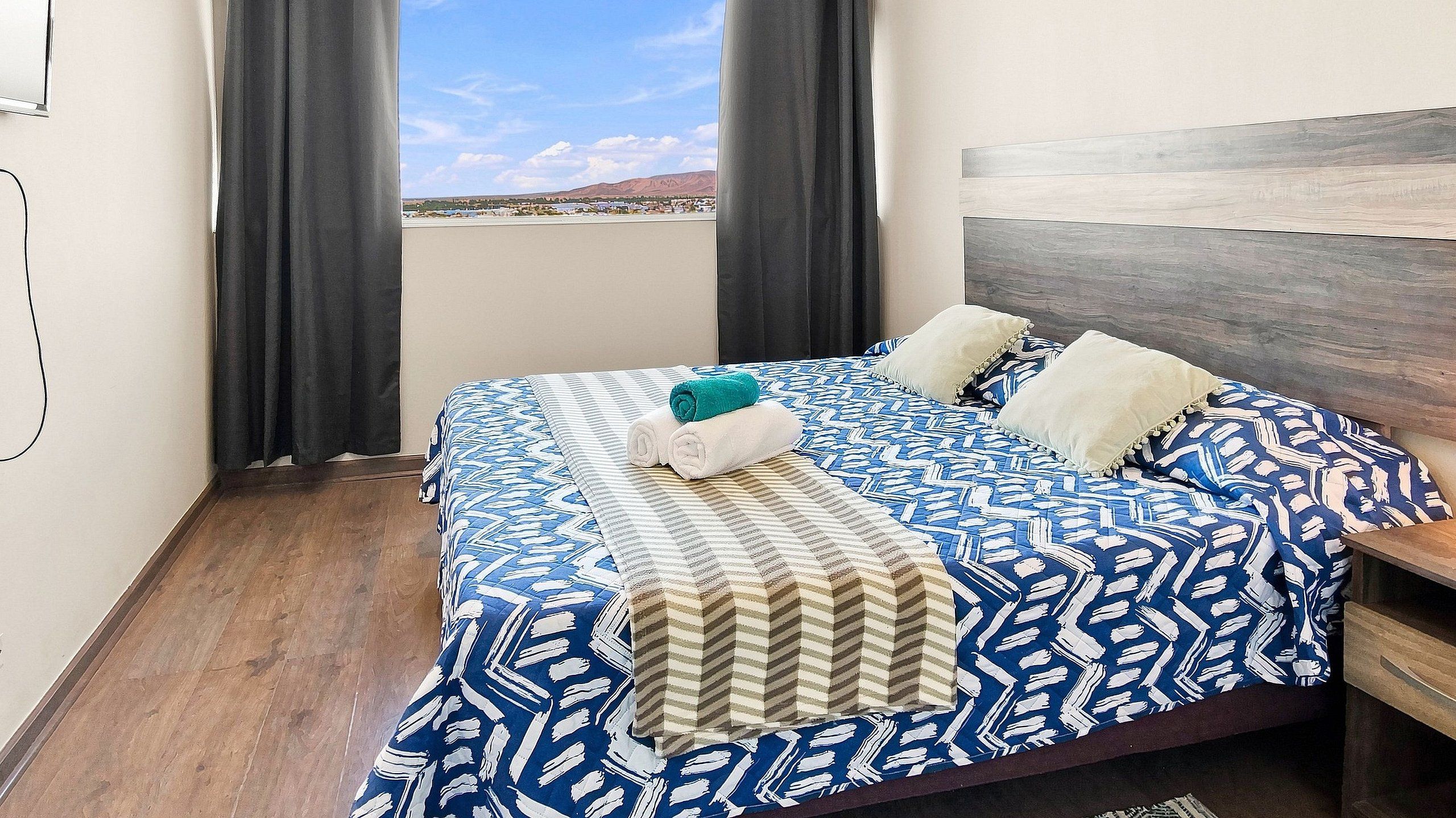 Una habitación de hotel con cama, cortinas y vistas a un paisaje.