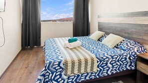 Quarto de hotel com uma cama, cortinas e vista para a paisagem.