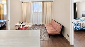 A hotel room with a sofa, a small table with a plant, and a patterned rug. - Oceana Suites Concepto One (Calama)