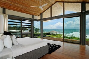 A modern bedroom with a large bed, a ceiling fan, and a view of the ocean. - Sava Villa 4 Villa Essenza (Takua Thung)