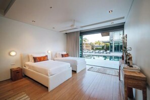 Habitación de hotel moderna con dos camas, un ventanal grande y vista a una piscina.