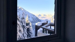 Ein Fenster mit Blick auf schneebedeckte Berge und einen klaren Himmel.