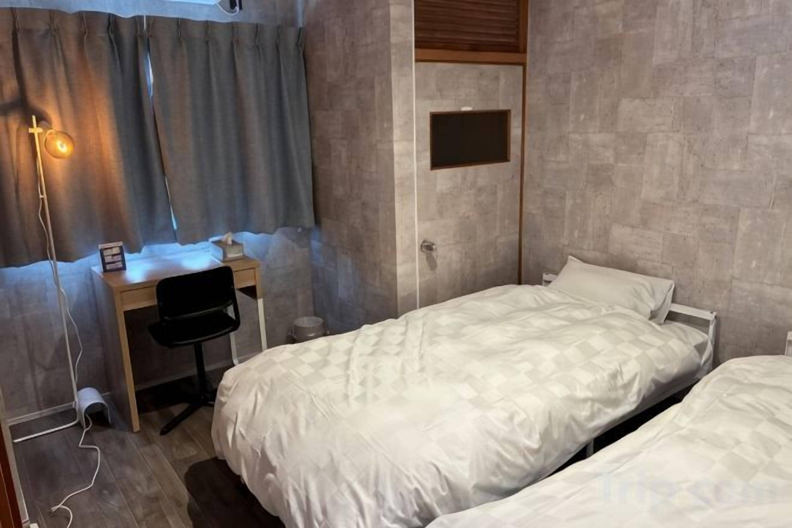 Un dormitorio con dos camas, un escritorio y una silla.