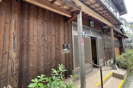 A wooden building with a traditional design, a wooden door, and a small outdoor area with steps.