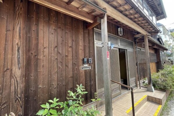A wooden building with a traditional design, a wooden door, and a small outdoor area with steps.