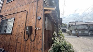 Un edificio de varios pisos con fachada de madera, un teléfono a la vista y una calle con otros edificios al fondo.