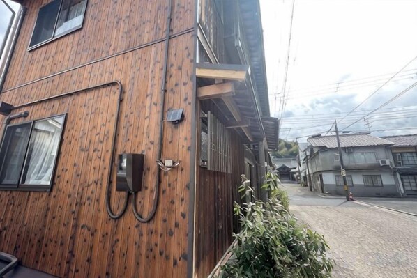 A multi-story building with a wooden facade, a visible telephone, and a street with other buildings in the background. - KYOTO TANGO MIYAZU inn (Miyazu)