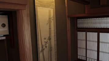 A traditional Japanese room with tatami flooring, a shoji screen, and a sliding door with bamboo artwork.