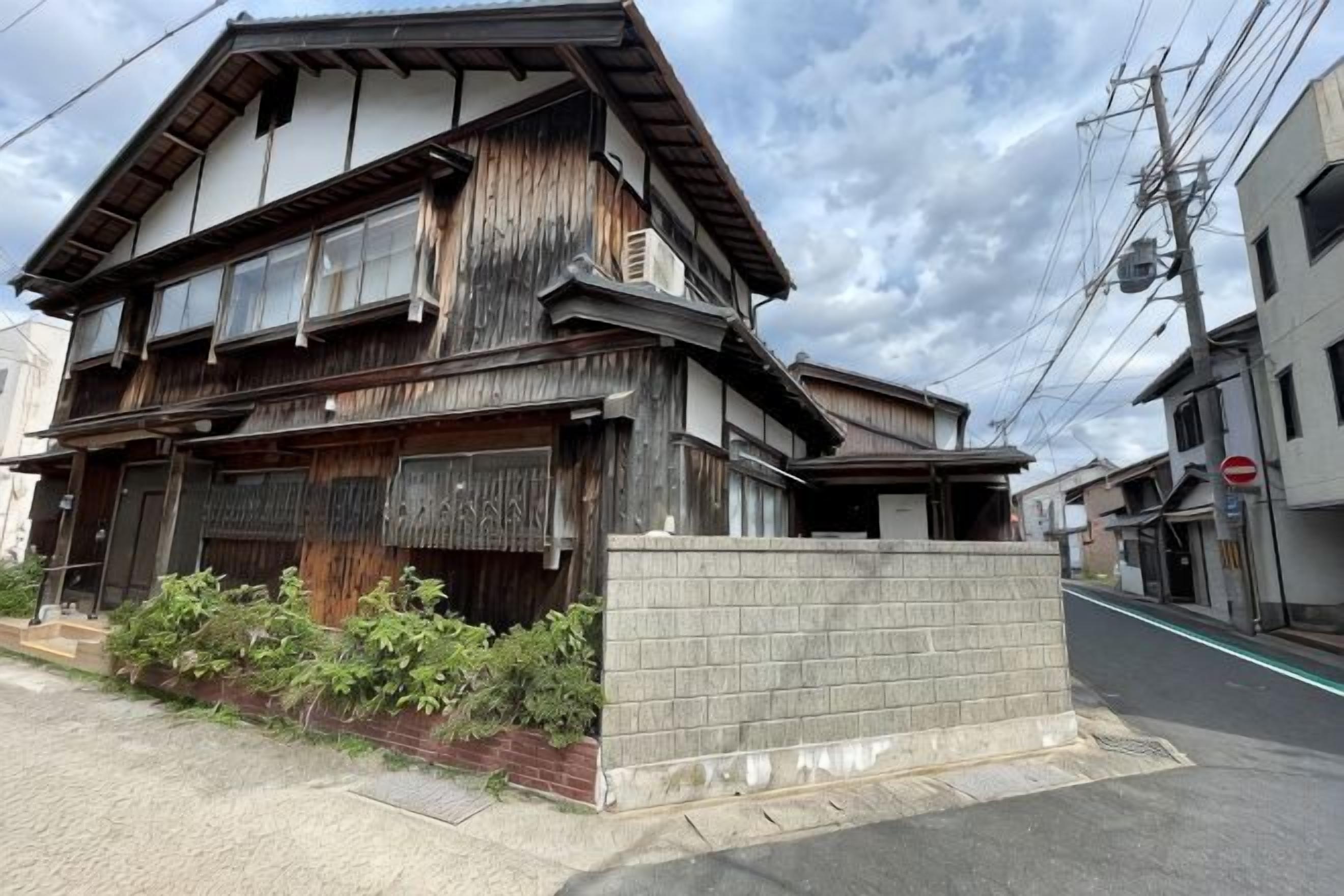 Un bâtiment à deux étages doté d’une façade traditionnelle en bois, d’un rez-de-chaussée en briques et d’un petit jardin à l’avant.
