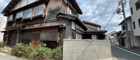Un bâtiment à deux étages doté d’une façade traditionnelle en bois, d’un rez-de-chaussée en briques et d’un petit jardin à l’avant.