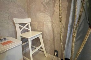 A white chair against a textured wall, a white cabinet with a label, and a curtain with a patterned border. - KYOTO TANGO MIYAZU inn (Miyazu)