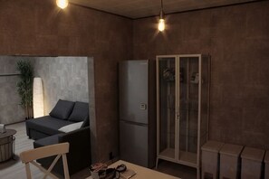 Ein gemütlicher, kompakter Wohnraum mit Sofa, Tisch, Kühlschrank und Schrank.