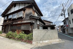 A two-story building with a traditional wooden facade, a brick base, and a small garden area with plants. - KYOTO TANGO MIYAZU inn (Miyazu)