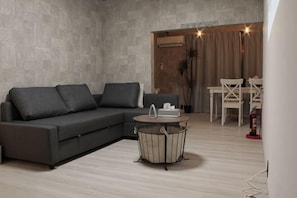 A modern living room with a sectional sofa, a round coffee table, and a dining area with a table and chairs.