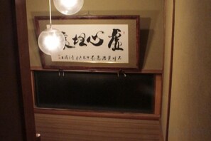 A framed sign with Japanese characters, a window below it, and a hanging light fixture. - KYOTO TANGO MIYAZU inn (Miyazu)
