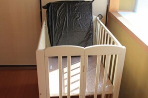 A white crib with a black sheet, positioned near a window with blinds. - KYOTO TANGO MIYAZU inn (Miyazu)