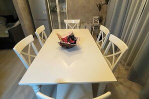 A dining table with six chairs, a basket of items, and a kitchen area in the background. - KYOTO TANGO MIYAZU inn (Miyazu)