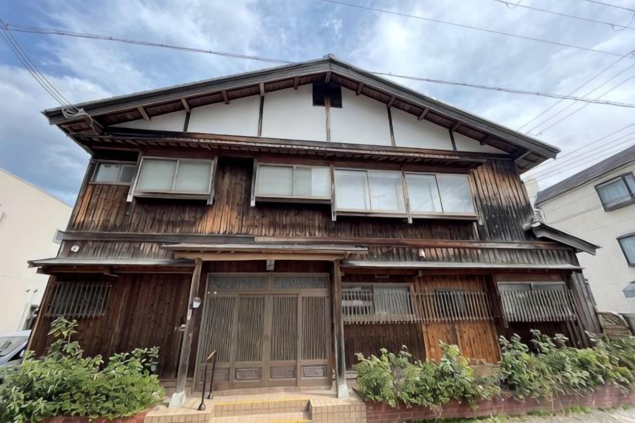 A traditional two-story building with a wooden facade, large sliding doors, and a tiled entrance.