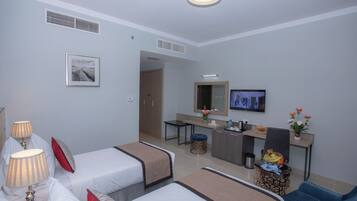 Habitación de hotel con dos camas, un escritorio, televisor y una pequeña kitchenette.