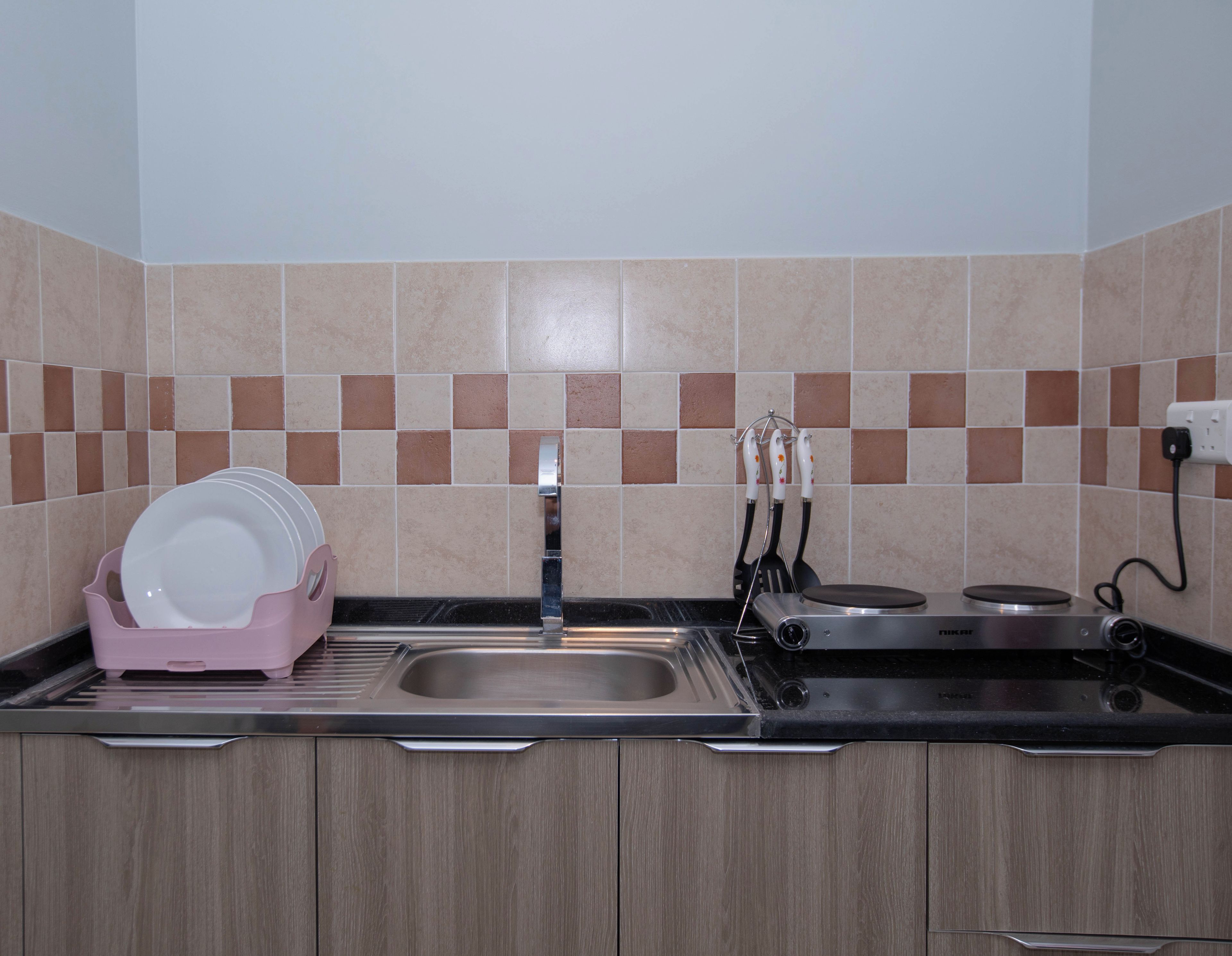 Cozinha com pia, bancada e painel de azulejos.