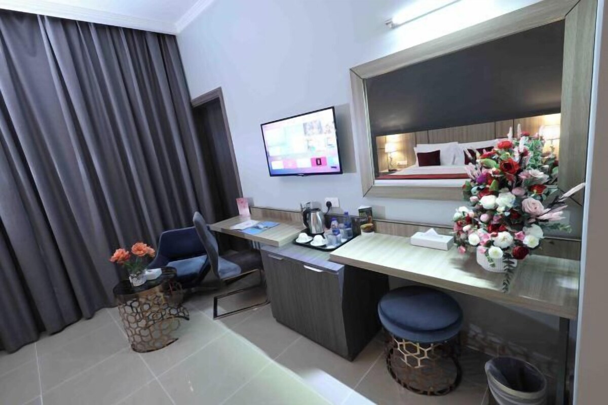 A modern hotel room with a desk, chair, TV, and a large mirror.