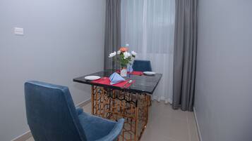 A dining area with a table, chairs, and a vase with flowers.