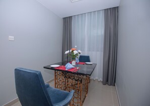 Een eetruimte met een tafel, stoelen en een vaas met bloemen.