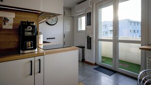A modern kitchen with a coffee machine, a clock, and a view of the outside. - RentPlanet - Apartament plac Nowy Targ (Wrocław)