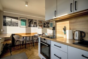 Eine moderne Küche mit Holztischplatte, Edelstahlgeräten und einem Essbereich mit Tisch und Stühlen.