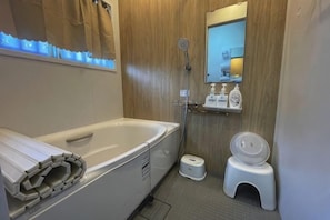 A bathroom with a bathtub, toilet, shower, and a mirror above the sink.