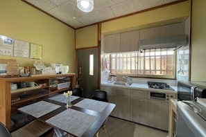 A kitchen with a stove, sink, and cabinets. There is a dining table with chairs and a small vase.