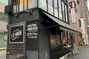 A building with a sign for 'Pizza Check' and a menu board advertising lunch and dinner times. - SunStay Fudomae (Tokyo)