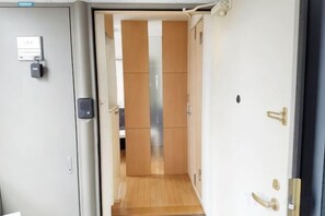 A hotel room entrance with a door, a keypad lock, and a view into the room. - SunStay Fudomae (Tokyo)