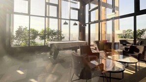 Une pièce spacieuse dotée de grandes fenêtres, d’une table de billard et de meubles modernes.