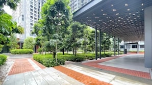 Un espace extérieur moderne doté d’une allée couverte, de verdure et d’un bâtiment en arrière-plan.
