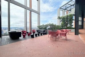 Una terraza en la azotea con mobiliario exterior y vistas de la ciudad.