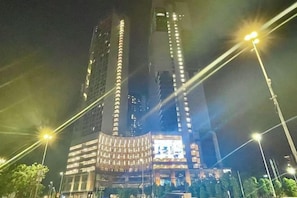 Un edificio de gran altura con ventanas iluminadas y una estructura curva destacada en la base.