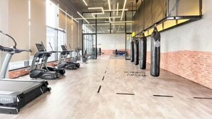 Une salle de sport équipée de tapis de course, de sacs de frappe et d’un espace dédié à la boxe.