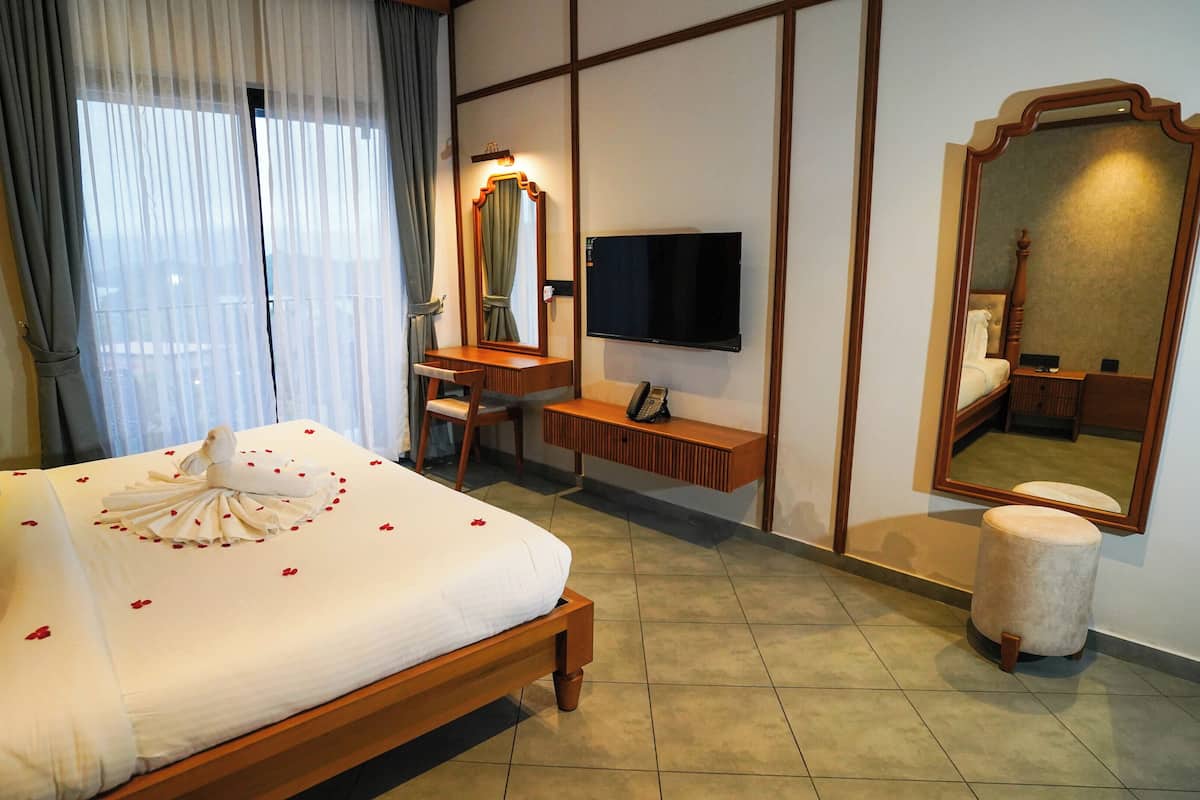 A hotel room with a bed, a desk, a television, and a large mirror.