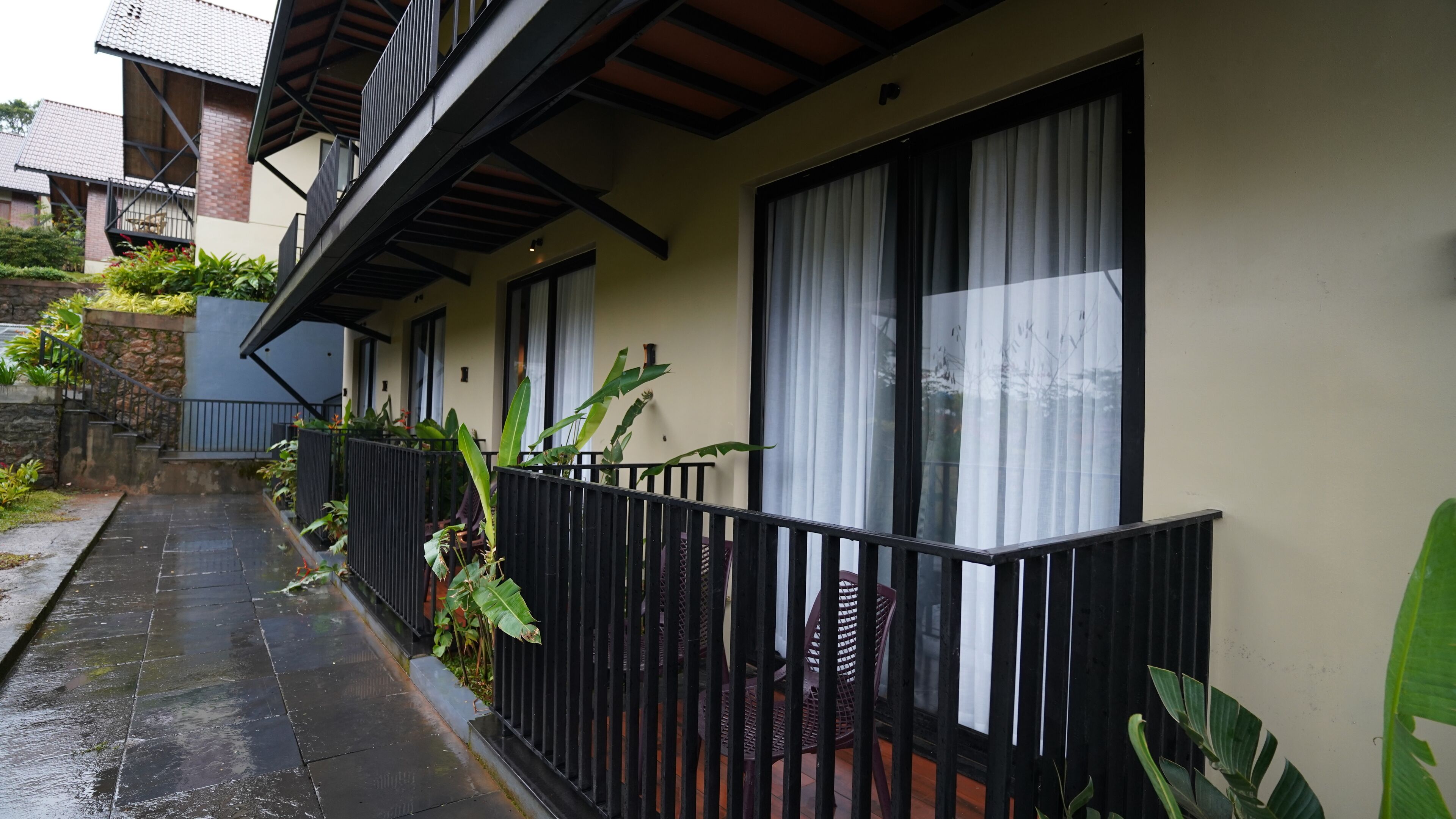 A residential building with a balcony, large windows, and a stone wall.
