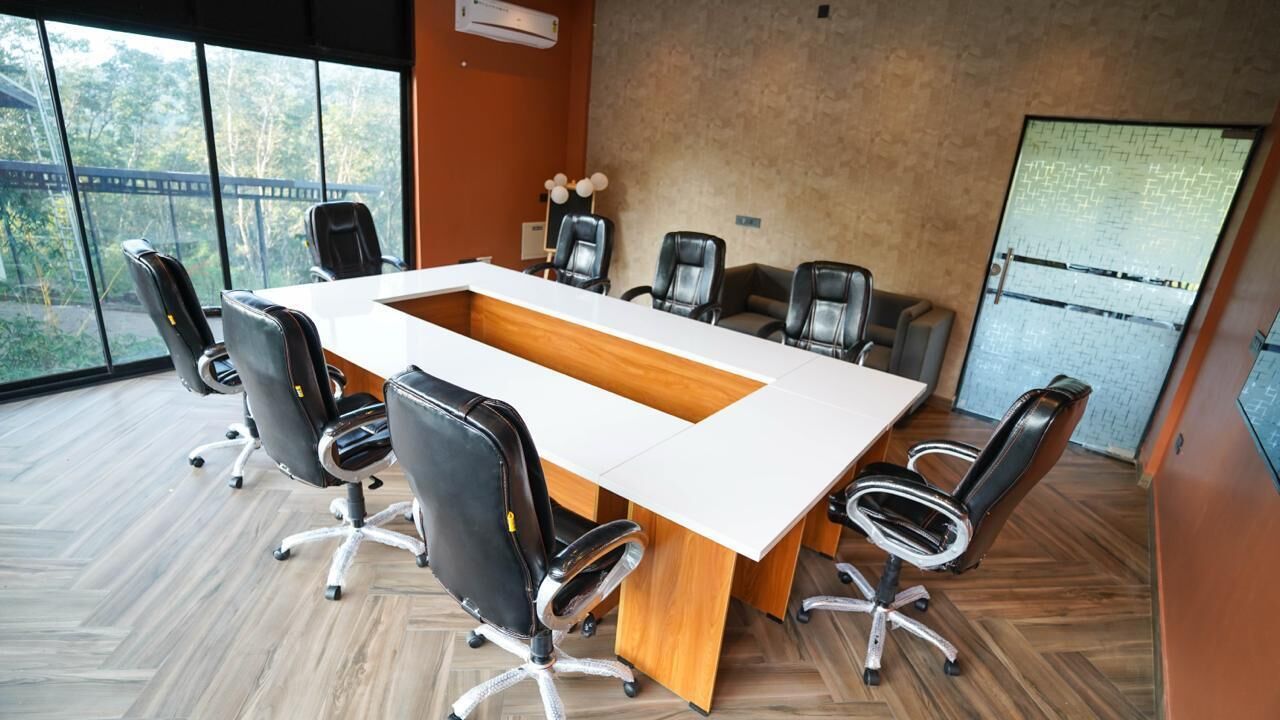 A conference room with a large table, six chairs, and a view through large windows.