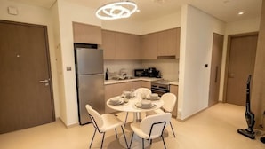 Uma cozinha moderna com área de jantar, incluindo uma mesa redonda com cadeiras, uma geladeira e um micro-ondas.