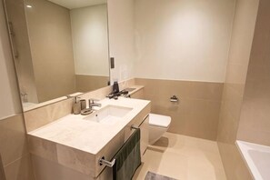 Une salle de bain moderne avec un grand miroir, un lavabo, des toilettes et une baignoire.