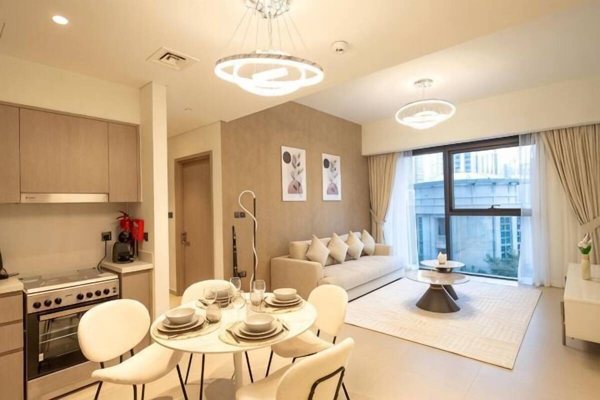 Una cocina moderna con comedor, sofá y un amplio ventanal con cortinas.
