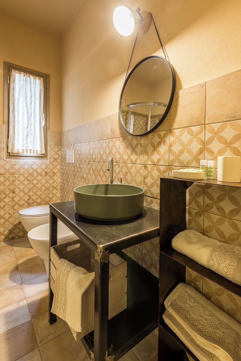 Un baño con un lavamanos redondo, un espejo y un inodoro.