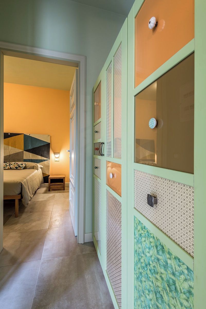 A hallway with a bed and a wardrobe with patterned doors.