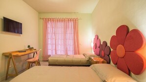 Quarto com duas camas, uma escrivaninha, uma cadeira e uma televisão na parede.