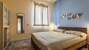 A bedroom with a wooden bed, beige curtains, and a blue wall with decorative plates. - Apartment No. 4 ( CIN: IT008031B48RJTC5CL Citra 008031-LT-1323 ) (Imperia)