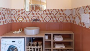 Un baño pequeño con lavadora, lavamanos y espejo.